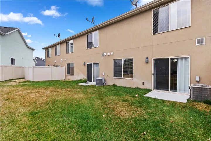 Rear exterior featuring stucco siding, multiple windows, and sliding glass door access to the outdoor space