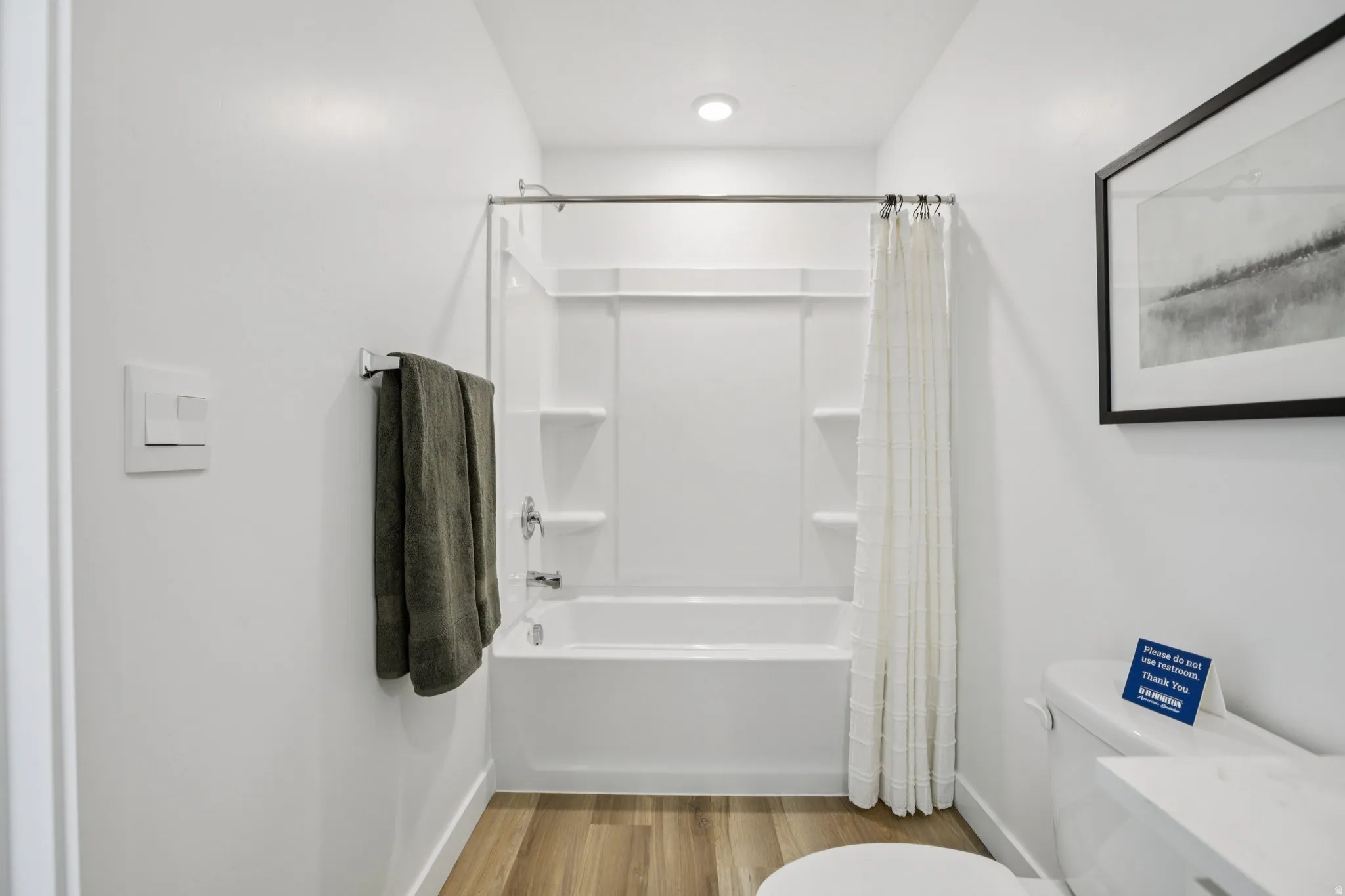 Contemporary bathroom with a white tub-shower combination, chrome fixtures, and wood-finish flooring