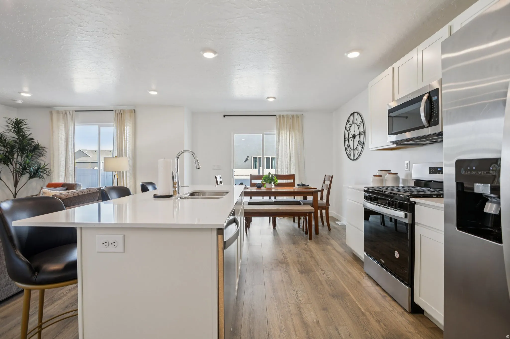 Open-concept kitchen with white cabinetry and wood-finish flooring