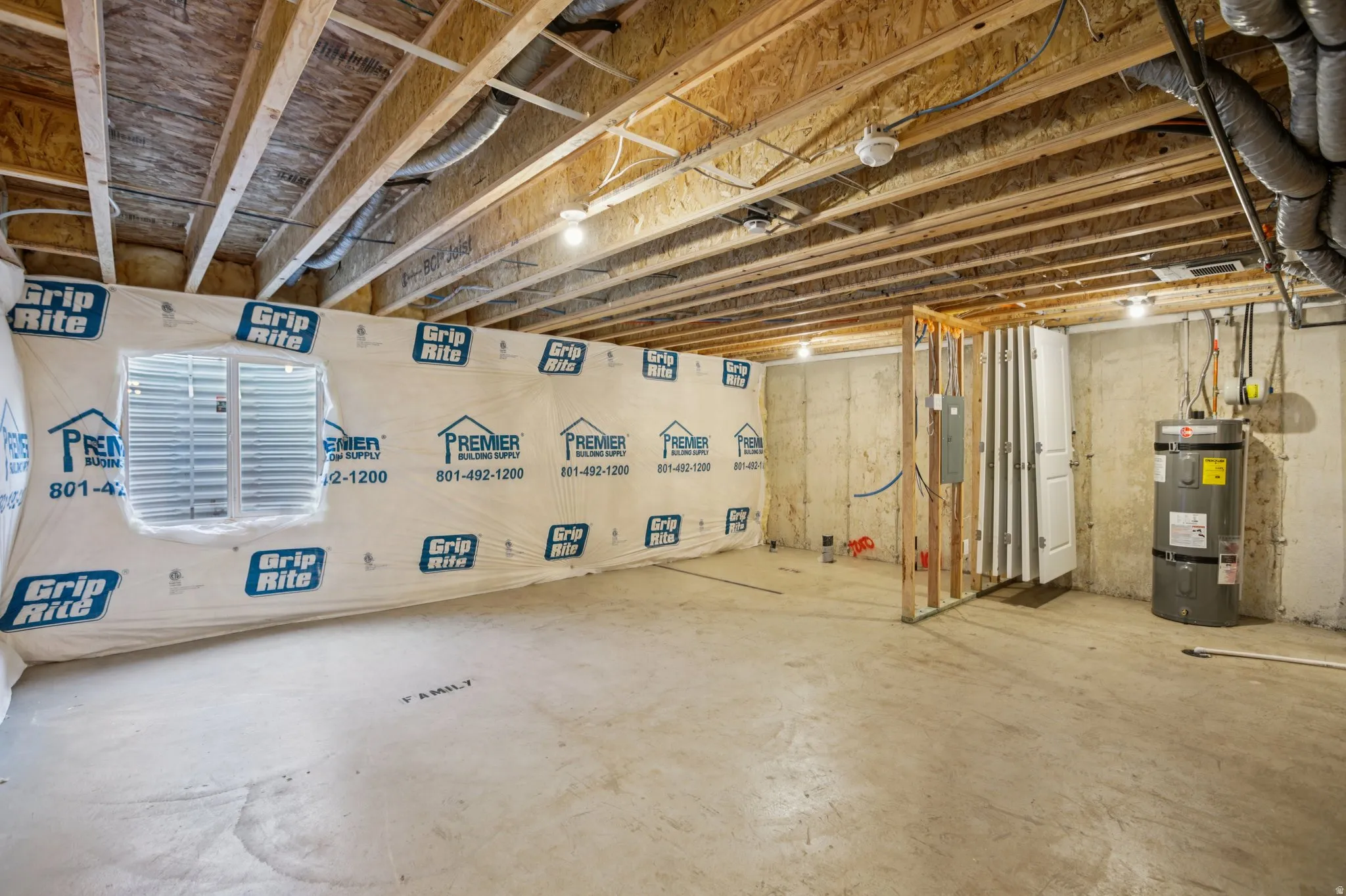 Unfinished basement featuring exposed wood joists, concrete flooring, a water heater, and a pre-framed utility area