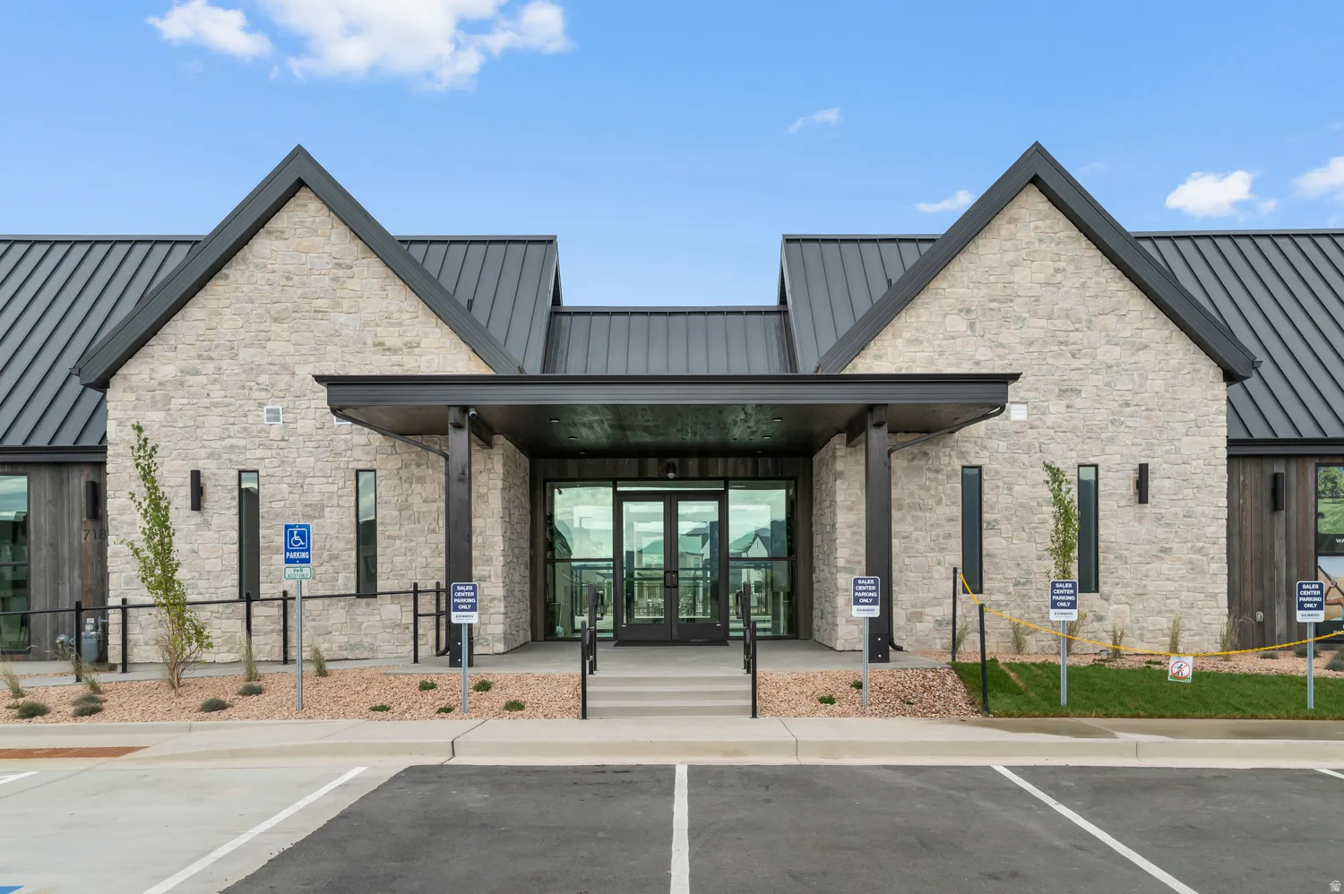Stone veneer facade with a black metal roof, glass double doors, and a covered entry