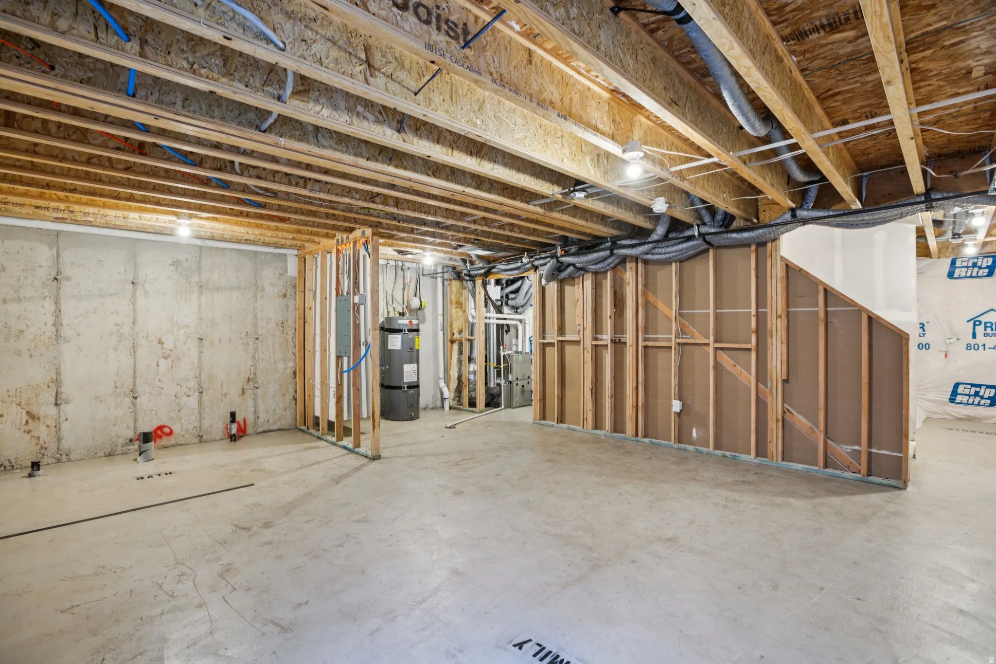 Unfinished basement with exposed concrete foundation walls, wood framing, and overhead joists