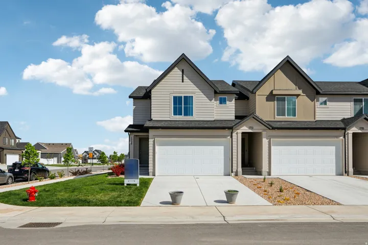Contemporary townhome exterior with mixed siding, attached garage, concrete driveway, and front landscaping