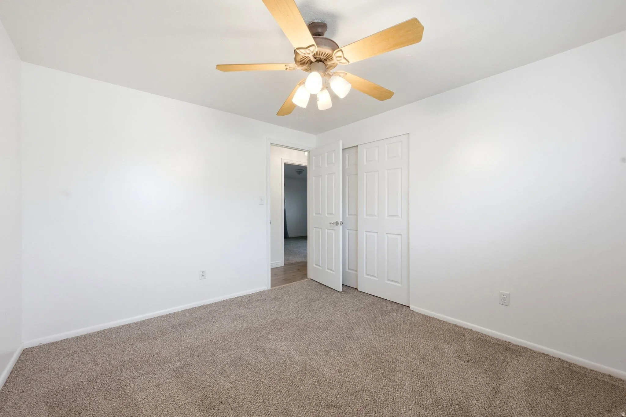 Neutral tone walls with textured carpeting, featuring a ceiling fan with integrated lighting