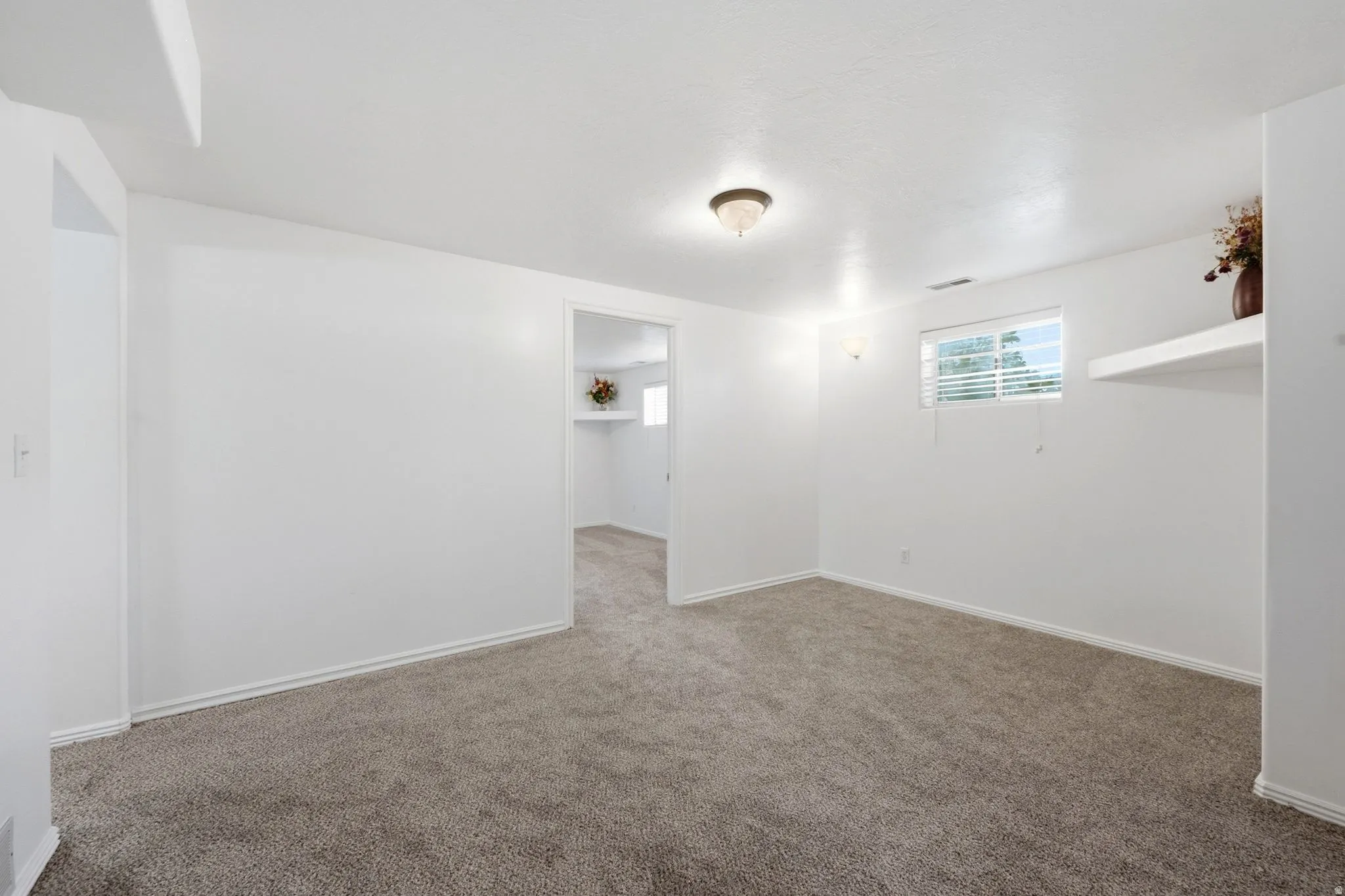 Spacious carpeted room with neutral wall finishes, recessed ceiling lighting, and abundant natural light from a high transom window