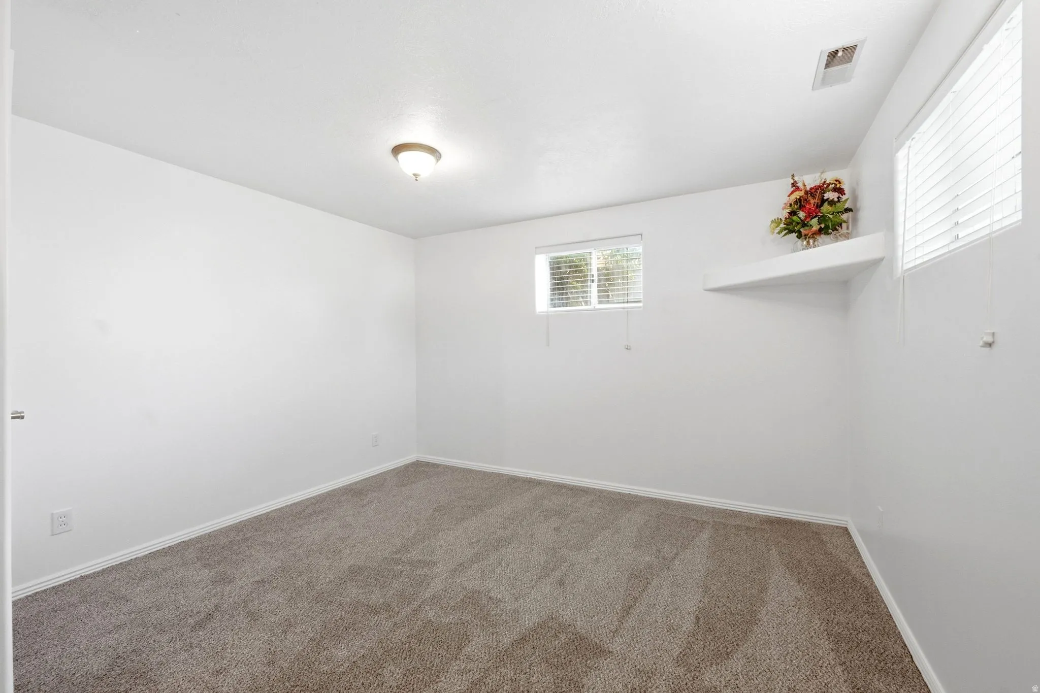 White walls, recessed window, built-in shelving, and carpeted flooring