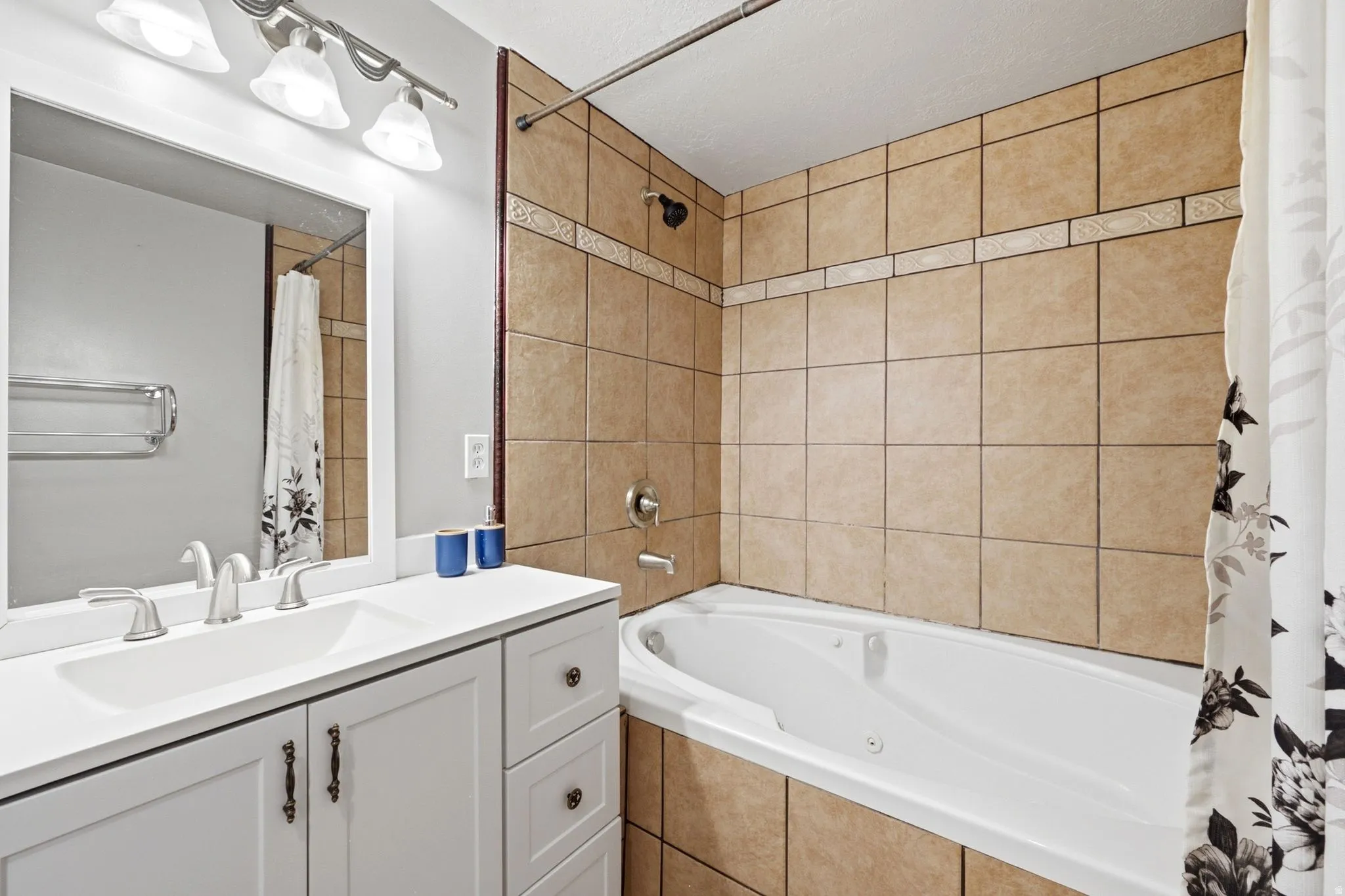 White vanity with integrated sink, brushed nickel faucet, and overhead lighting