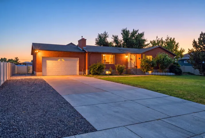 Brick exterior with an attached garage, concrete driveway, and front lawn landscaping