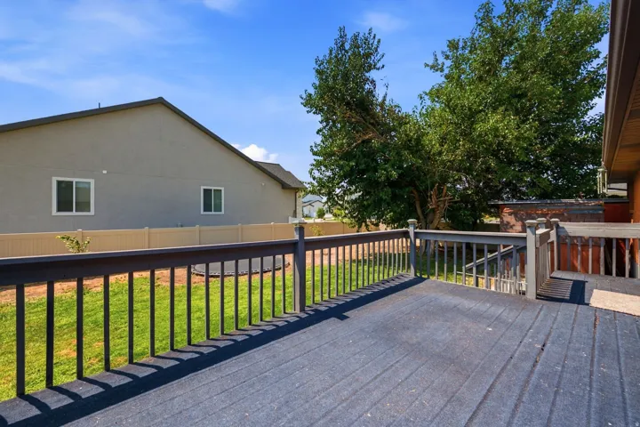 Spacious outdoor deck with dark wood-finish flooring, dark-stained railings, and a direct walk-out to the yard