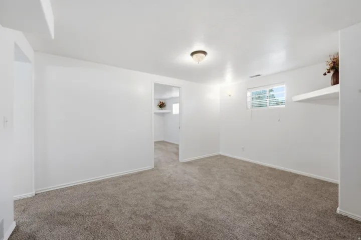 Spacious carpeted room with neutral wall finishes, recessed ceiling lighting, and abundant natural light from a high transom window