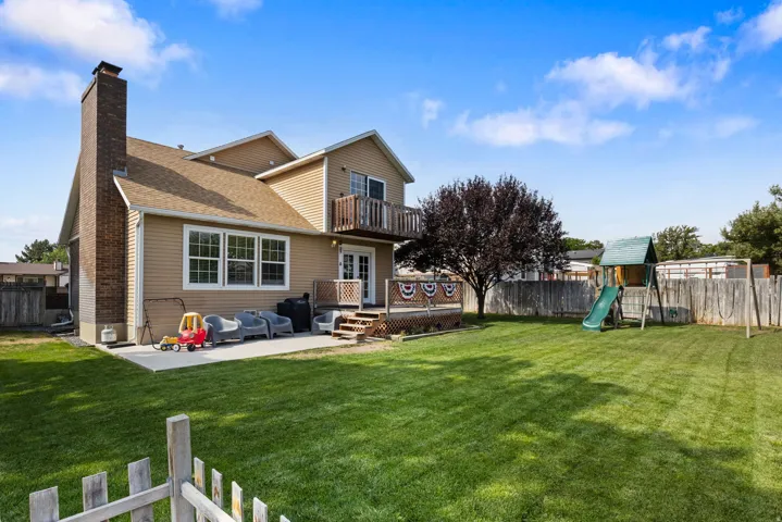 Expansive backyard featuring a manicured lawn, wood fencing, and a mature tree