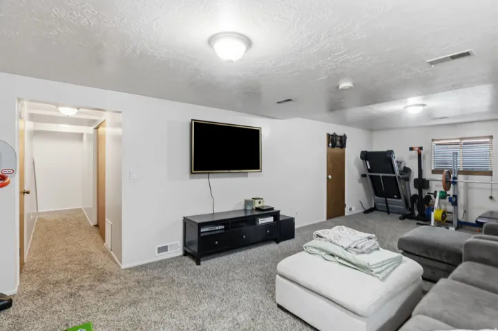 Recessed ceiling lighting illuminates a spacious room featuring wall-to-wall carpeting and neutral wall tones