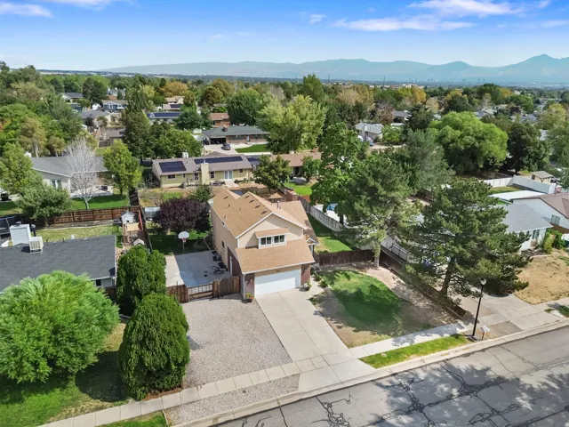 Two-story residence with an attached garage, featuring a paved driveway, a fenced perimeter, and mature landscaping