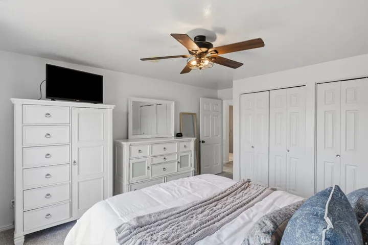 Ceiling fan with integrated lighting, white walls, and multiple bi-fold closet doors
