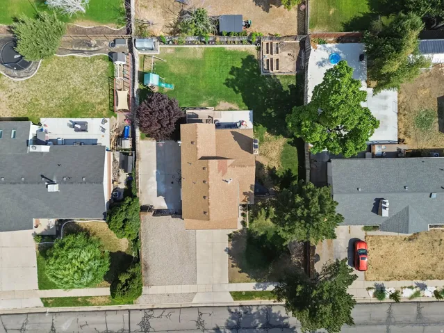 Paved driveway with ample parking, gabled roofline, and established landscaping
