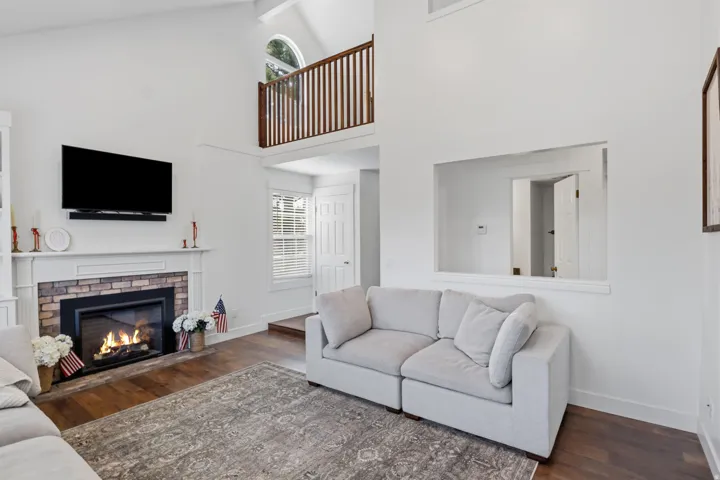 Vaulted ceilings and a stone-surround fireplace with a classic white mantel