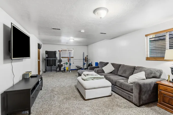 Carpeted recreational room with recessed lighting and a window featuring blinds
