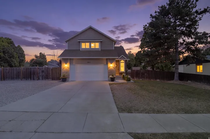 Two-story residence featuring an attached two-car garage, concrete driveway, and established landscaping