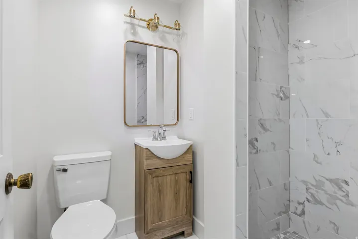 Powder room featuring a wood-finish vanity with a vessel sink, a rectangular framed mirror, and a gold-tone vanity light