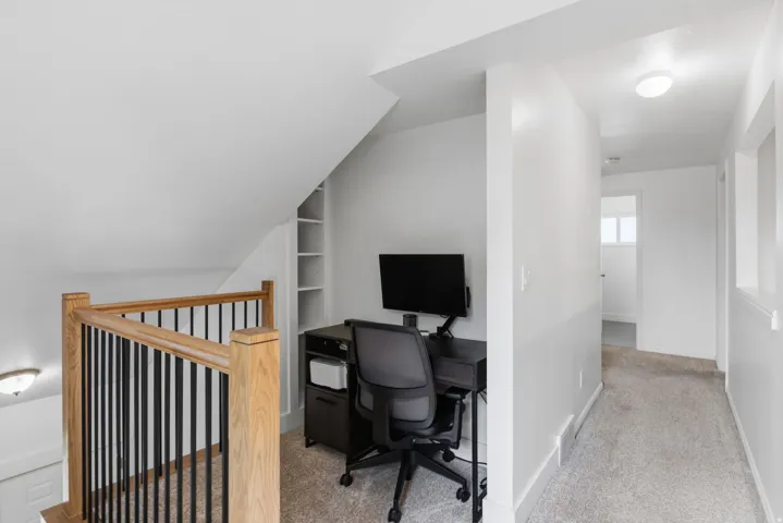 Built-in shelving, wood-finish railing with black spindles, and recessed lighting