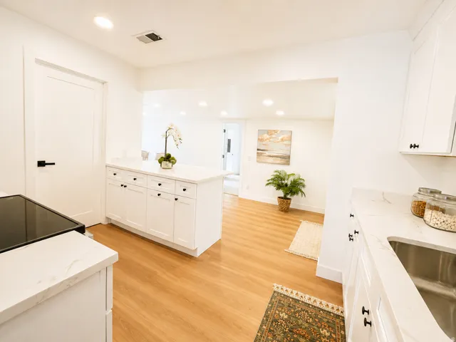 White shaker cabinetry with black hardware, white countertops, stainless steel sink, wood-finish flooring, and recessed lighting