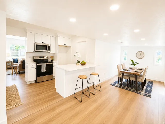 Modern kitchen with white cabinetry, stainless steel appliances, a center island with countertop seating, and wood-finish flooring