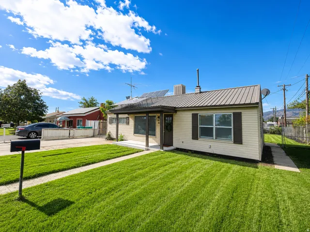 Cream-toned siding residence with a metal roof and dark shutters