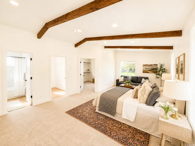 Exposed wood ceiling beams, recessed lighting, and light-toned carpeting