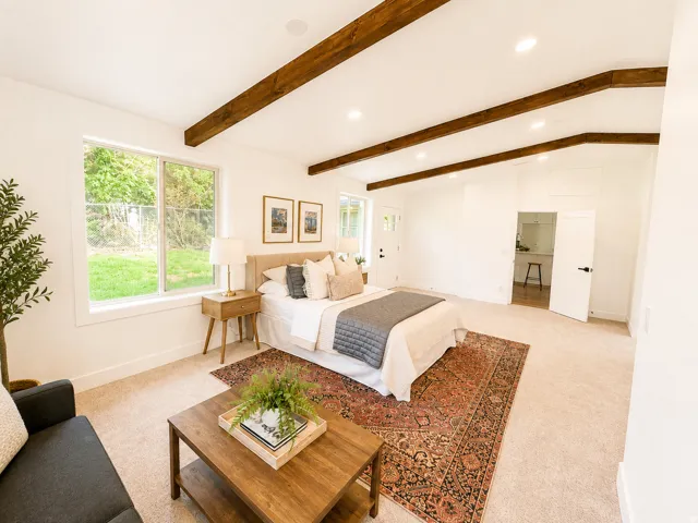 Vaulted ceiling with exposed wood beams, recessed lighting, and large windows