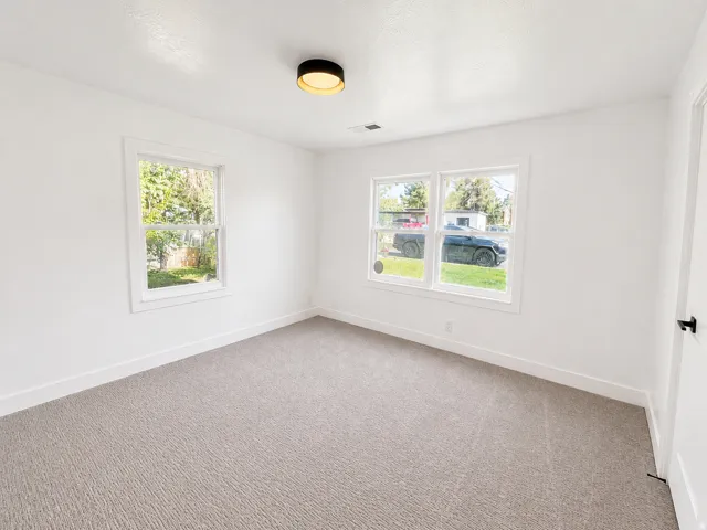Newly installed carpeting, white painted walls, and a modern ceiling-mounted light fixture