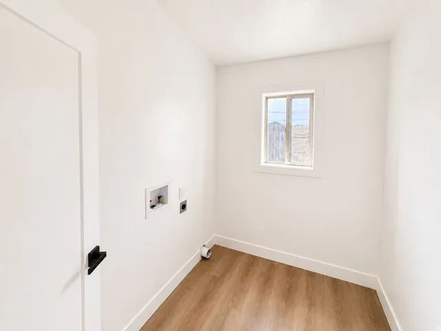 Dedicated utility space featuring a window, wood-finish flooring, and white trim