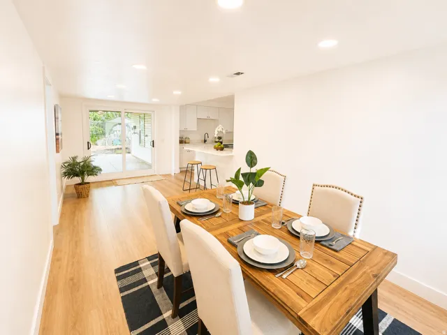 Recessed ceiling lighting illuminates the dining area, featuring wood-finish flooring and white walls