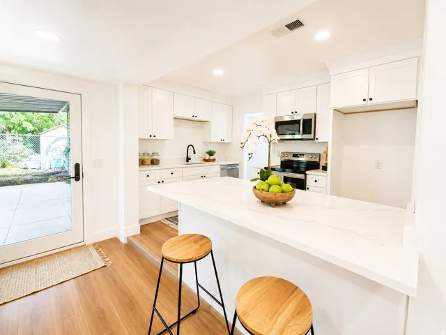 Kitchen featuring white cabinetry, stainless steel appliances, a white countertop, wood-finish flooring, and a glass-paneled exterior door