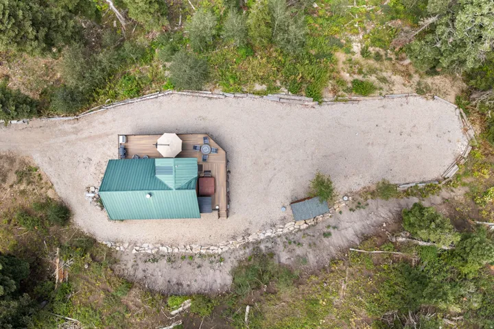 Compact structure with a green metal roof and a wood-finish deck