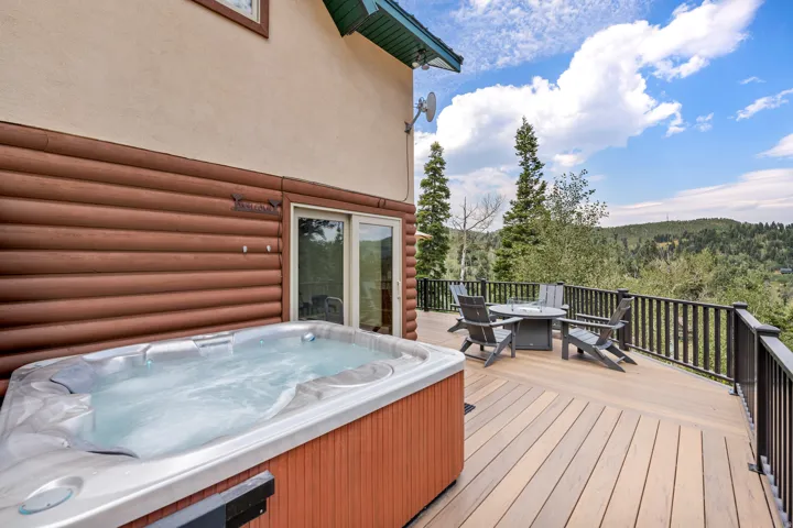 Expansive composite deck featuring warm wood-finish decking and black aluminum railings, anchored by a spa-style hot tub with integrated seating