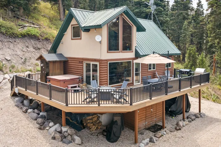 Cabin-style exterior featuring a green metal roof and large glass-paned windows