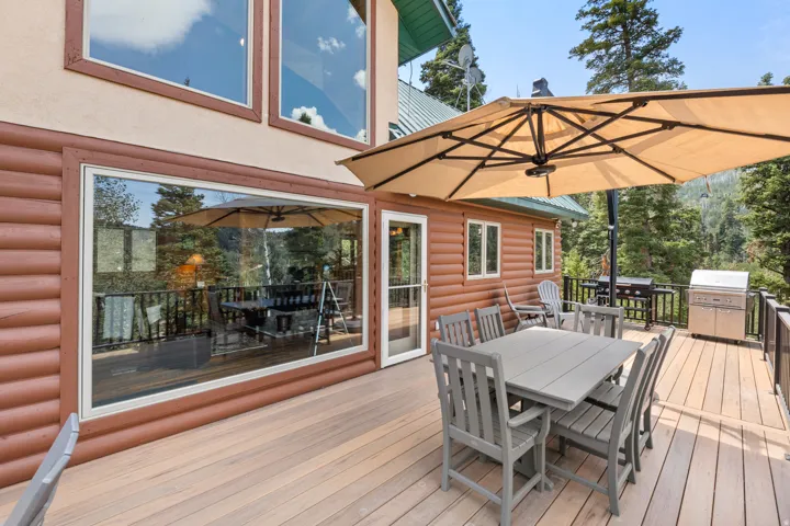 Spacious outdoor deck with composite decking, log siding exterior, and large windows