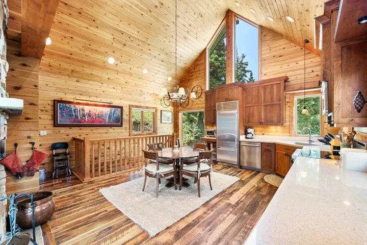 Vaulted wood-paneled ceilings, extensive wood-finish flooring, stone fireplace, stainless steel appliances, and large windows