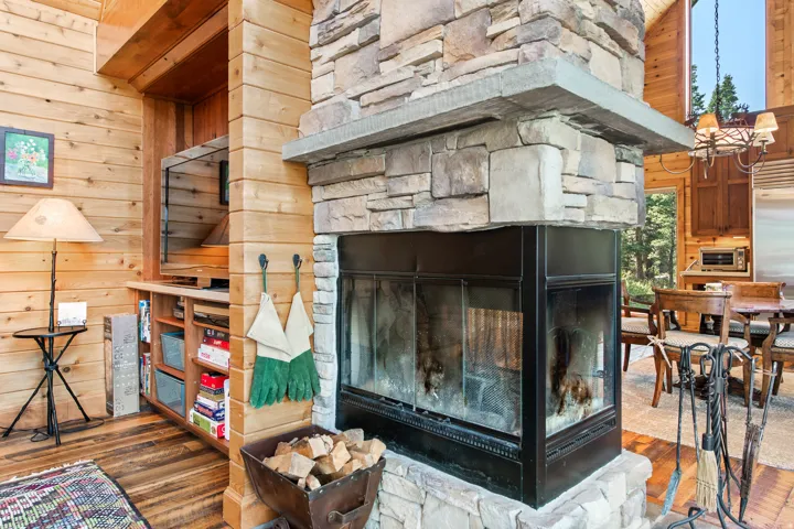 Stone-clad fireplace with a hearth, wood-paneled walls, built-in shelving, and wood-finish flooring