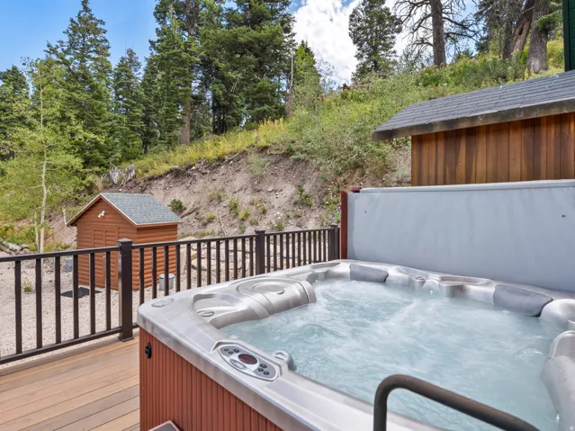 Deck with a built-in hot tub, black metal railing, and wood-finish siding