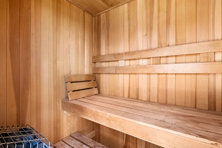 Wood-paneled interior with built-in wooden benches and a heater with rocks