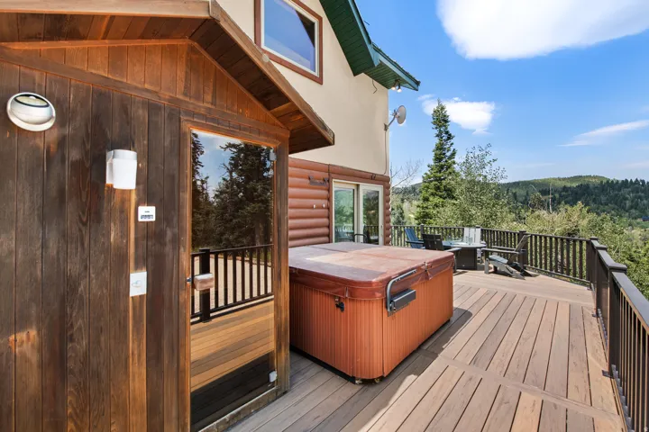 Expansive outdoor deck featuring wood-finish flooring, a built-in outdoor sauna, and a spa