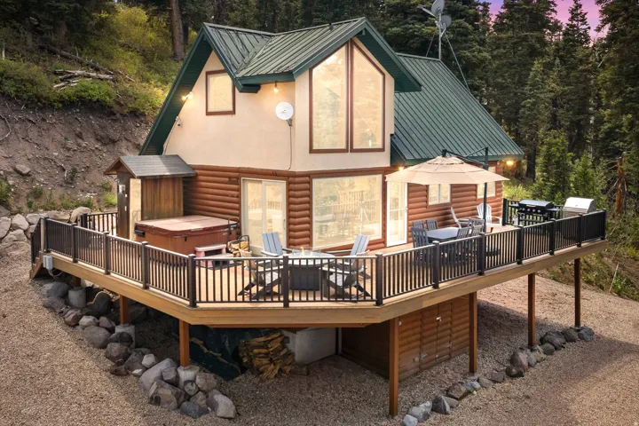 Multi-level elevated deck with a hot tub, log siding, a metal roof, and large windows