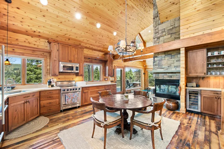 Vaulted wood-paneled ceilings, stone fireplace, wood-finish flooring, custom wood cabinetry, and stainless steel appliances
