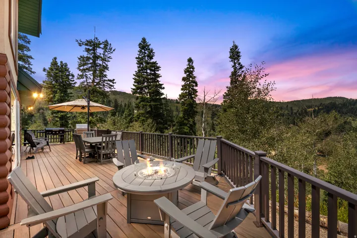 Expansive outdoor deck with wood-finish decking, dark brown railings, and a built-in fire pit