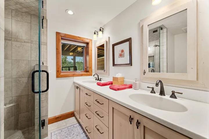 Dual vanity with light-toned cabinetry and integrated sinks, complemented by individual framed mirrors