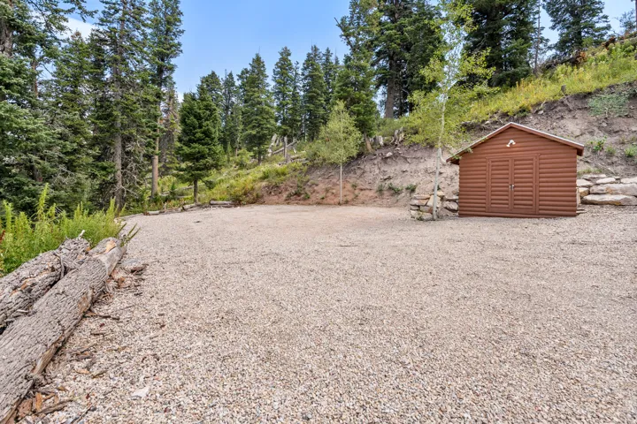 Gravel pad with a freestanding storage shed and natural tree surroundings