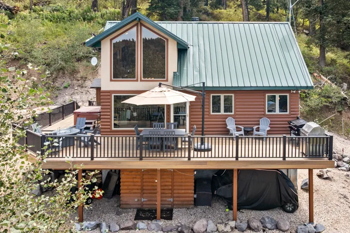 Expansive multi-level deck, log siding exterior, large floor-to-ceiling windows, metal roof, and integrated hot tub