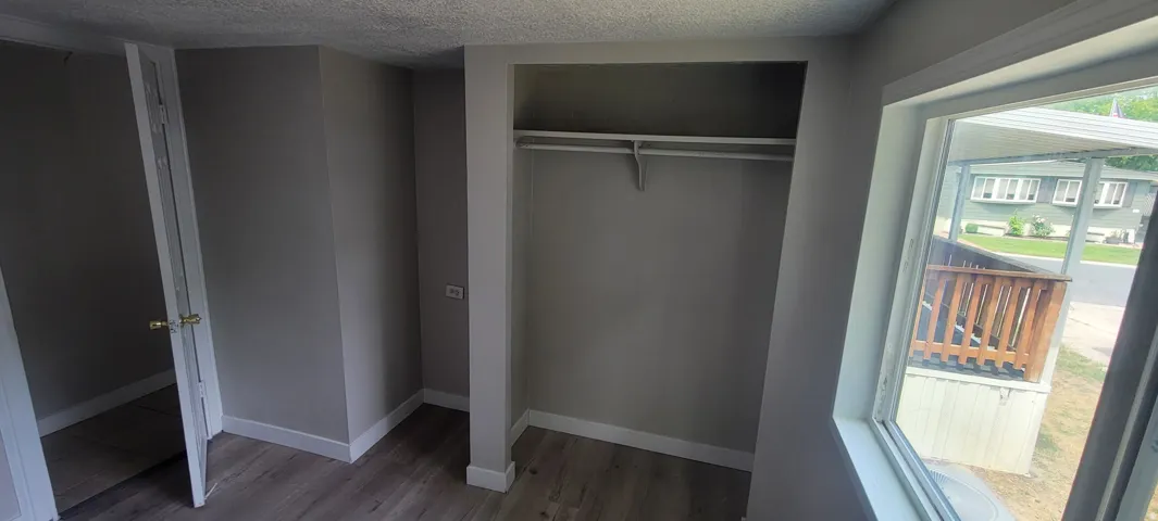 Wood-finish flooring, neutral painted walls, built-in closet storage, and a single pane window