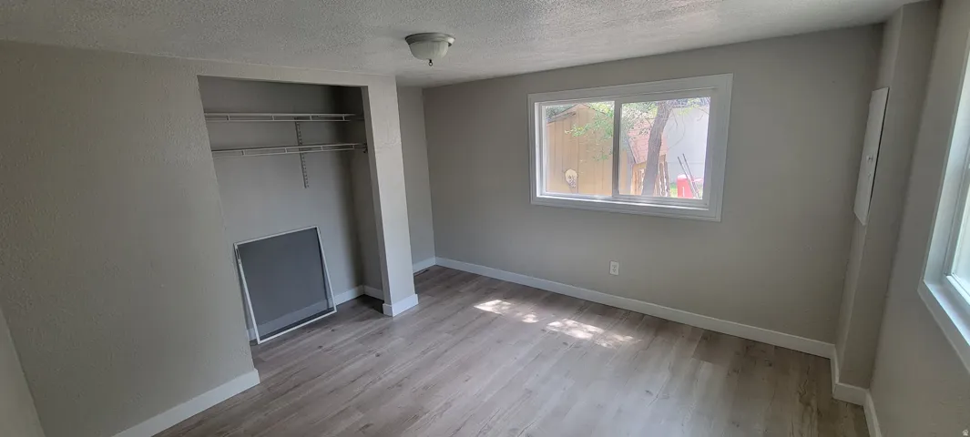Wood-finish flooring, neutral wall tones, and a window with white trim